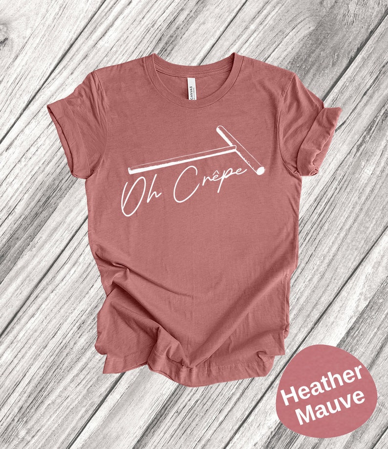 May include: A heather mauve t-shirt with a white graphic of a crepe maker and the text "Oh Cr&ecirc;pe".