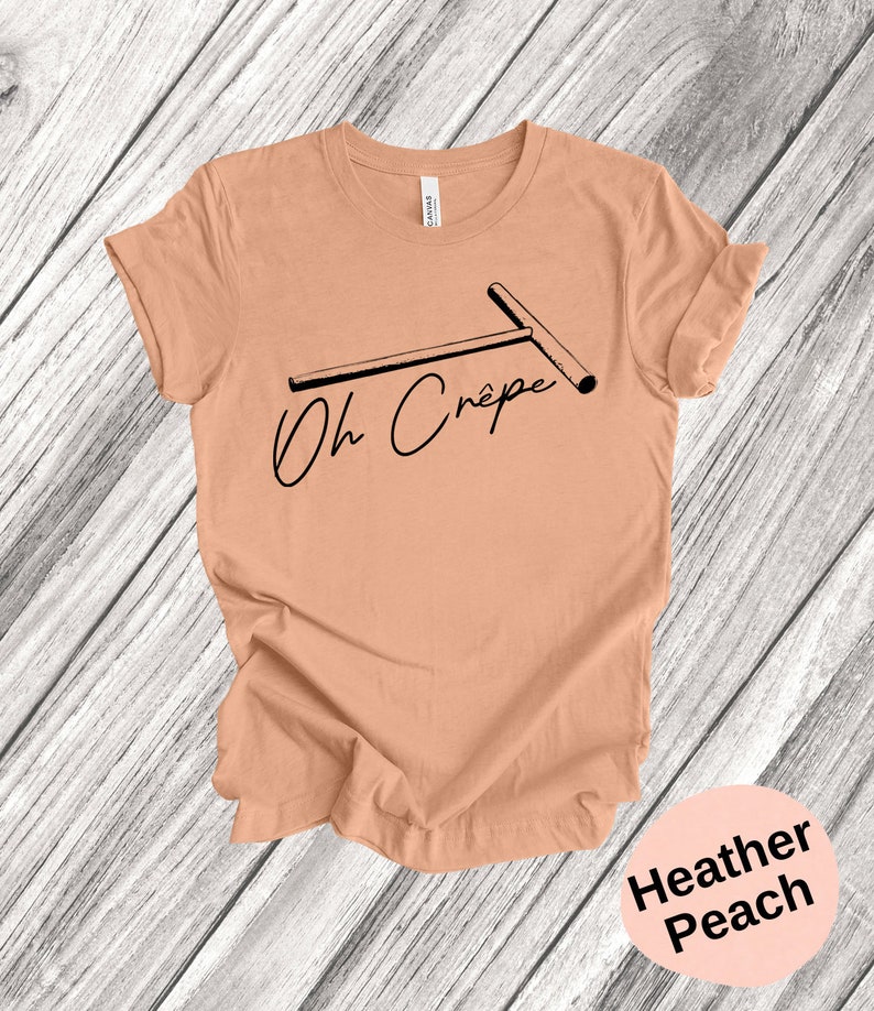 May include: A heather peach t-shirt with a black graphic of a crepe maker and the text "Oh Cr&ecirc;pe".