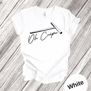 May include: White t-shirt with a black and white illustration of a crepe maker and the text "Oh Cr&ecirc;pe".