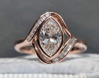 Puede incluir: Un anillo de oro rosa con un diamante central de talla marquesa rodeado por un engaste de estilo bypass. La banda está acentuada con pequeños diamantes de talla baguette rectangular a lo largo de los lados curvos, creando un marco fluido.