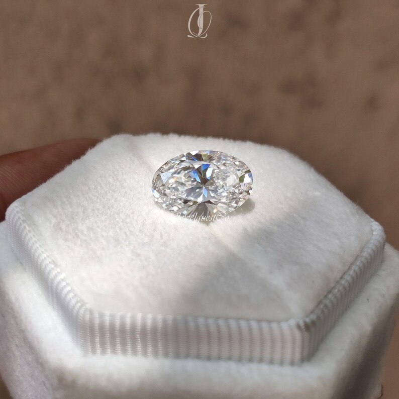 Close-up image of a brilliant oval cut lab grown diamond resting on a soft white velvet background, displaying its exceptional fire and clarity. The expertly faceted surface captures and reflects light beautifully, showing the premium craftsmanship of an ethical, conflict-free lab created diamond. Ideal as a loose stone for custom engagement rings, this oval cut diamond symbolizes sustainability, modern elegance, and responsible luxury for eco-conscious couples seeking timeless sparkle.
