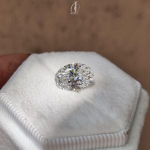 A stunning oval cut lab-grown diamond with fire and brilliance visible through professional tweezers. An ideal choice for eco-conscious customers seeking custom jewelry pieces.