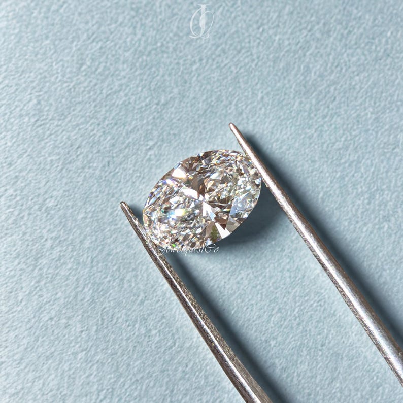Loose oval cut diamond displayed against a light blue background, showcasing pristine clarity and cut symmetry, crafted in lab conditions to provide a sustainable and affordable alternative to mined diamonds.