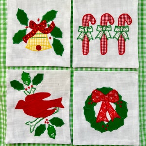 May include: Four white Christmas-themed decorative squares. One features a bell with a red bow and holly, another has three candy canes with green bows, a third shows a red bird on a branch, and the last has a wreath with a red bow.