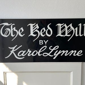 Op de afbeelding: Een zwart-wit bord met de tekst "The Bed Mill by Karol Lynne" in een cursief schrift.