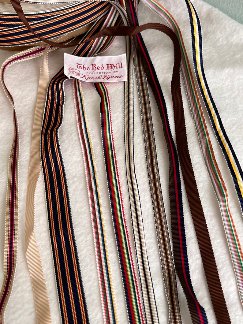 Op de afbeelding: Assortiment van kleurrijke gestreepte lintrollen met een label met de tekst "The Red Mill Collection by Karol Lynne".