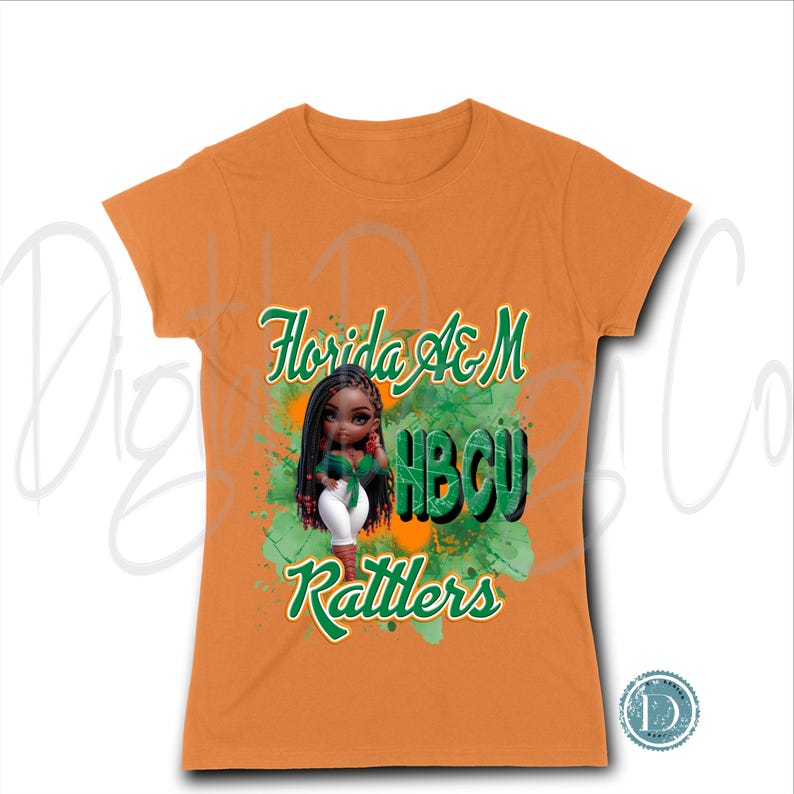 May include: Orange t-shirt featuring a graphic of a doll with long black hair, wearing a green top and white pants. The shirt has the words "Florida A&M HBCU Rattlers" in green and white script. The graphic is set against a green and orange splatter design.