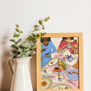 May include: A framed illustration of two women in colorful clothing sitting at a table with a pink tablecloth. They are enjoying a meal with tea, sweets, and a pitcher of milk. The illustration is in a modern style with bold colors and patterns.
