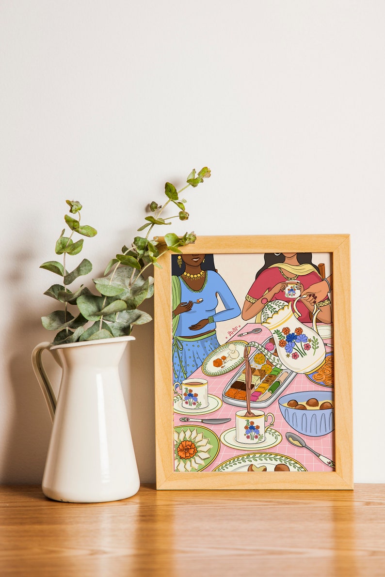 May include: A framed illustration of two women in colorful clothing sitting at a table with a pink tablecloth. They are enjoying a meal with tea, sweets, and a pitcher of milk. The illustration is in a modern style with bold colors and patterns.