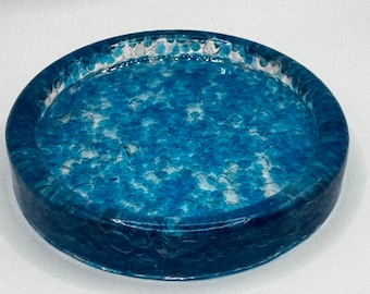 Könnte beinhalten: Ein rundes, blaues Harztablett mit einer strukturierten Oberfläche. Das Tablett hat ein weißes, gesprenkeltes Design im Inneren.