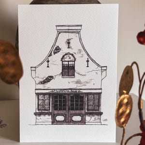 May include: Pen and ink drawing of a building facade with a Dutch gable. The building has a central arched window, two doors, and two windows. The text "TJ'S & WAYEL SALON" is above the doors. The drawing is on textured paper.