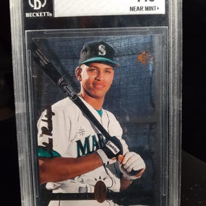 May include: A graded 1994 SP Alex Rodriguez baseball card. The card is encased in a clear plastic holder and has a Beckett grading of 7.5 Near Mint+. The card features a photo of Alex Rodriguez in a Seattle Mariners uniform holding a baseball bat.