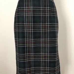 Op de afbeelding: Een donkergroene geruite rok met een klassiek patroon. De rok heeft een herhalend patroon van donkergroene, witte, rode en gele lijnen. De rok heeft een rechte snit en lijkt gemaakt van een geweven stof.