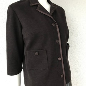 Op de afbeelding: Een bruin blazer met een satijnen bies en een enkele klepzak. De blazer heeft een knoopsluiting en een kraag.
