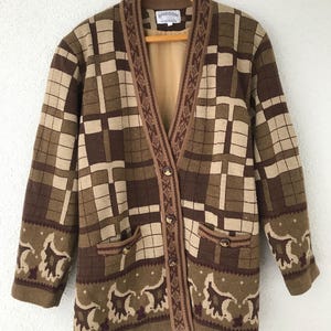 May include: A vintage brown and tan plaid cardigan sweater with a V-neck, long sleeves, and decorative pockets. The sweater has a unique pattern on the cuffs and trim, and is buttoned up the front. The label reads "BRIECOM AUSTRALIA".