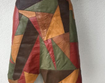 Könnte beinhalten: Ein mehrfarbiger Patchwork-Lederrock. Der Rock hat geometrische Formen in Rot-, Braun-, Grün- und Orangetönen. Er hat einen ungewöhnlichen, asymmetrischen Saum.
