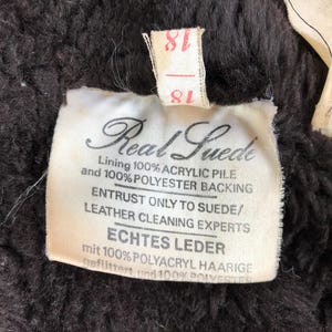 K&ouml;nnte beinhalten: Ein wei&szlig;es Etikett mit schwarzem Text, der "Real Suede" und "Entrust only to suede/leather cleaning experts" und "Echtes Leder mit 100% Polyacryl haarige gefilttert und 100% Polyester" lautet.