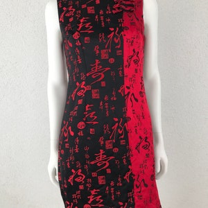 Könnte beinhalten: Ärmelloses schwarz-rotes Kleid mit chinesischen Schriftzeichen. Das Kleid hat einen Stehkragen und eine rote Seitenbahn. Die schwarze Seite ist mit roten chinesischen Schriftzeichen bedeckt. Das Kleid ist knielang.