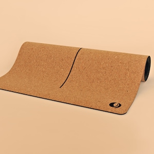 May include: A rolled up cork yoga mat with a black line down the center and a black logo on the bottom right corner.