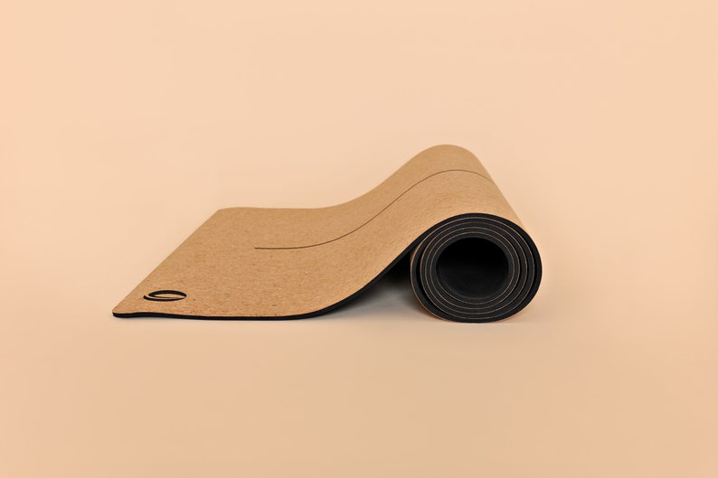 May include: A rolled up cork yoga mat with a black border. The mat has a light brown color and is rolled up tightly.