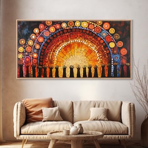 May include: Abstract painting with a warm color palette, featuring a sun-like design with concentric circles in shades of orange, yellow, and red. The artwork includes a row of silhouetted hands reaching upwards, set against a dark background, framed in a wooden frame.