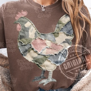 Pode incluir: Camiseta marrom com um design de galinha em patchwork em tons de verde, rosa e jeans. A camiseta tem um visual desgastado. O texto "The Crafty Shop" é visível. Um carimbo que diz "ORIGINAL DESIGN" também é visível.