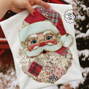 May include: White t-shirt with a Santa Claus face design. The Santa face is made of patchwork fabric with red, pink, and beige patterns. Santa wears a red hat, gold glasses, and has a white beard. The text "The Crafty Shop" is visible.