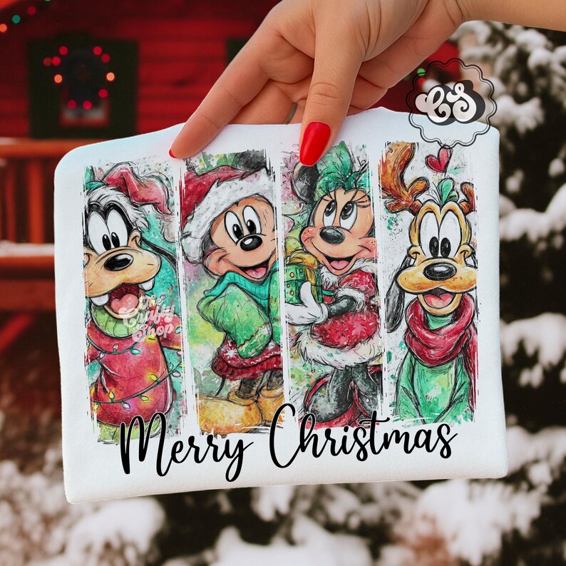 Puede incluir: Camiseta blanca con un dise&ntilde;o navide&ntilde;o que presenta a Goofy, Mickey Mouse, Minnie Mouse y Pluto con trajes festivos. Las palabras "Merry Christmas" est&aacute;n impresas en una fuente cursiva. Los personajes est&aacute;n dispuestos en un patr&oacute;n de rayas verticales.