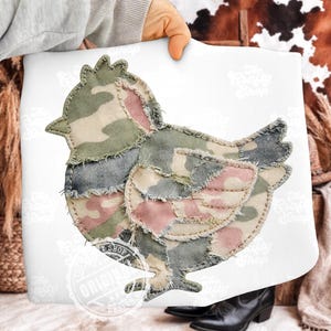 May include: A white pillow featuring a patchwork chicken design. The chicken is made of camouflage fabric in shades of green, pink, and denim blue. The pillow has the text "The Crafty Shop" and "Original Design".