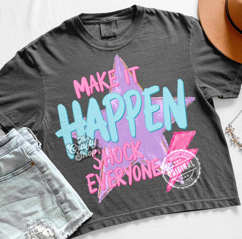 Może przedstawiać: Ciemnoszara koszulka z napisem "MAKE IT HAPPEN SHOCK EVERYONE" w r&oacute;żowych i niebieskich literach na fioletowym wzorze gwiazdy. Zawiera r&oacute;żową błyskawicę i okrągłe logo. Casualowy element mody.