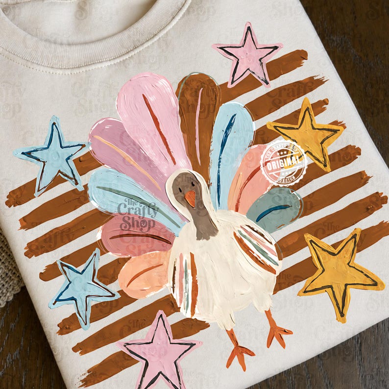 May include: A cream-coloured sweatshirt featuring a graphic print of a turkey with a fanned tail in shades of pink, blue, and brown. The design includes brown horizontal brushstrokes and five-pointed stars in pink, light blue, and yellow.