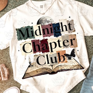 Op de afbeelding: Wit t-shirt met de tekst "Midnight Chapter Club" in een gelaagd ontwerp. Het ontwerp bevat een volle maan, een vlinder, een open boek en een kaars. Het shirt is van het merk Comfort Colors.
