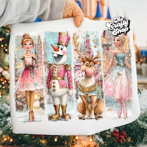 Puede incluir: Tela blanca con cuatro paneles con ilustraciones de acuarela. Los paneles representan a una princesa con un vestido rosa, un muñeco de nieve con uniforme rosa, un reno con abrigo azul y una princesa con un vestido azul y rosa. El logotipo de The Crafty Shop es visible.