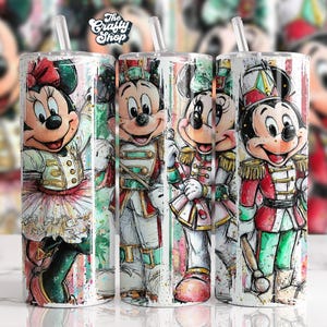 Könnte beinhalten: Vier Edelstahlbecher mit Illustrationen von Mickey und Minnie Mouse in festlicher Kleidung. Die Becher haben einen Strohhalm und ein farbenfrohes Design mit Aquarell-Effekt. Das Logo The Crafty Shop befindet sich oben.