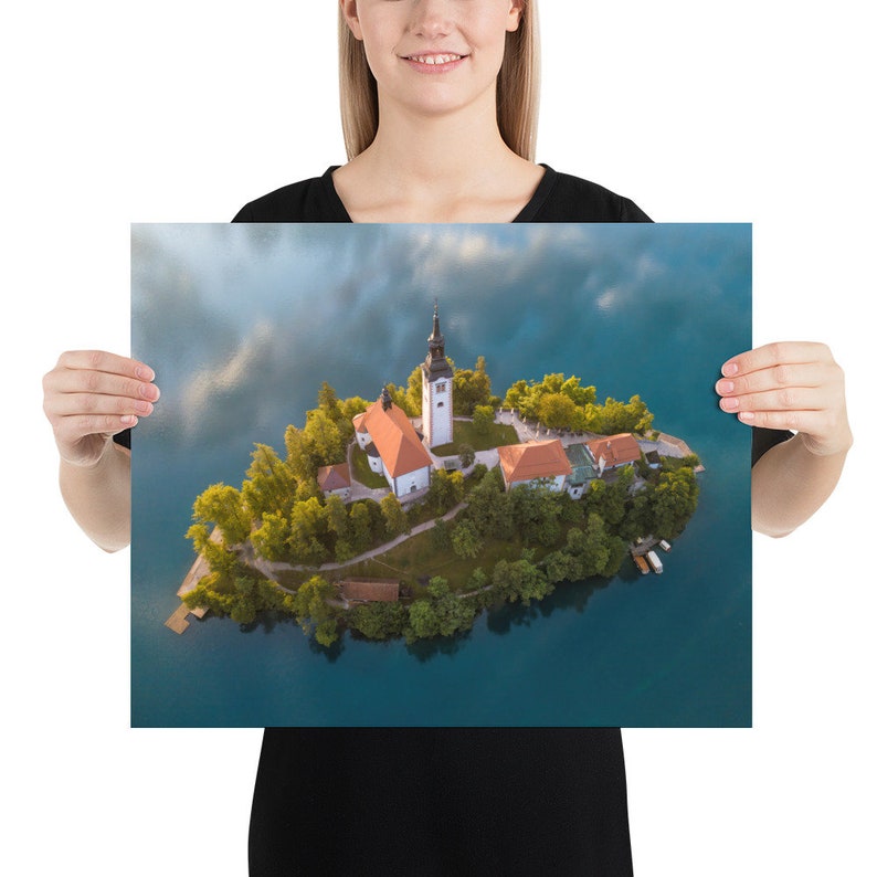 Puede incluir: Una impresi&oacute;n en p&oacute;ster que muestra una vista a&eacute;rea de una peque&ntilde;a isla con una iglesia y edificios rodeados de agua turquesa. La isla est&aacute; cubierta de &aacute;rboles verdes y tiene un muelle. La iglesia tiene un alto campanario blanco y un tejado rojo.