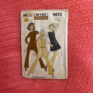 May include: A vintage sewing pattern for a dress and pants set. The pattern is from le-roy Weldons and is for size 12, bust 34 inches. The pattern is printed on a white background with brown and yellow illustrations of the garments.