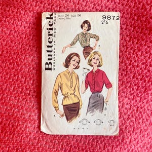 Könnte beinhalten: Vintage-Schnittmuster für eine Bluse, Größe 14, Brustumfang 86 cm. Das Schnittmuster ist von Butterick, entworfen in New York. Die Schnittmuster-Nummer ist 9872 2/6. Das Schnittmuster zeigt drei verschiedene Stile von Blusen mit langen Ärmeln.