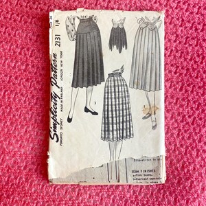 May include: A vintage Simplicity sewing pattern for a skirt, pattern number 2131 1/6. The pattern shows three different skirt styles, one with a plaid print and two with solid fabric. The pattern is printed on a cream-colored paper with black text.