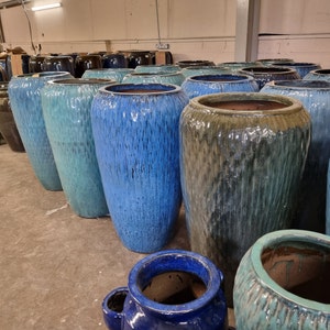 May include: A collection of blue and green glazed ceramic planters of various sizes. The planters are arranged in a row, with the largest planter in the centre.