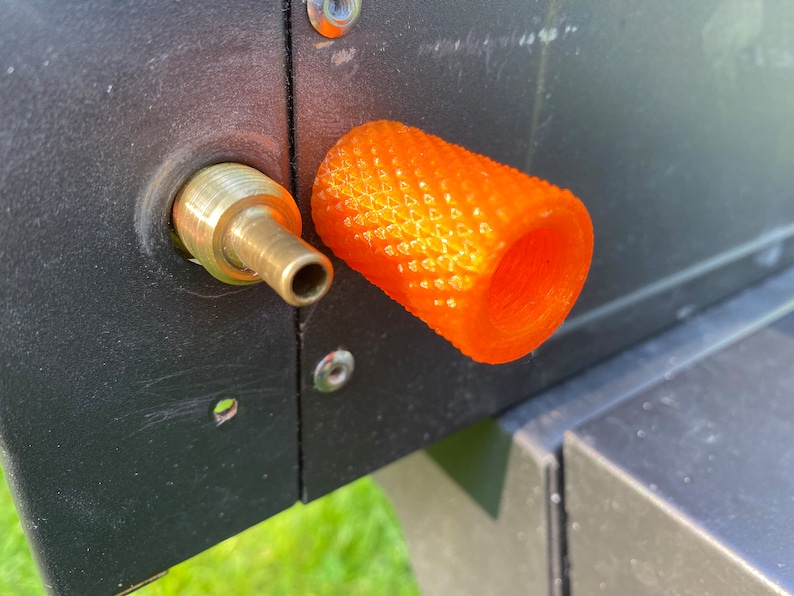 Puede incluir: Primer plano de una tapa de v&aacute;lvula de pl&aacute;stico naranja con una superficie texturizada. La tapa est&aacute; unida a una v&aacute;lvula de metal.