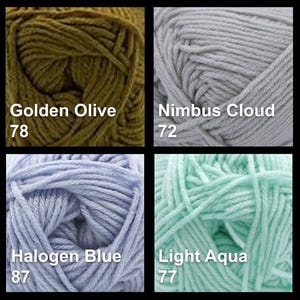 May include: Four skeins of yarn in various colors: Golden Olive, Nimbus Cloud, Halogen Blue, and Light Aqua. Each skein is labeled with its color name and a number. The yarn is tightly wound, showing the texture of the fibers.