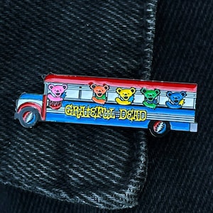 May include: A red, white, and blue school bus pin with the text "Grateful Dead" on the side. Five colorful bears are sitting in the windows of the bus.