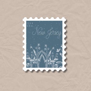 May include: A postage stamp featuring a blue background with white floral illustrations and the words "New Jersey" in cursive. The stamp also includes the text "20¢ USA". The stamp has a white border with a scalloped edge.