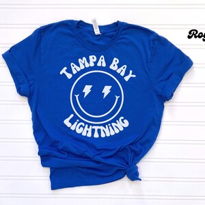 May include: Royal blue t-shirt with a white smiley face graphic and the text "Tampa Bay Lightning".