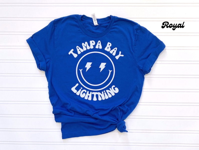 May include: Royal blue t-shirt with a white smiley face graphic and the text "Tampa Bay Lightning".