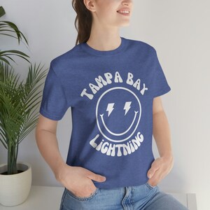 May include: A blue t-shirt with a white smiley face graphic and the text "Tampa Bay Lightning" in a retro font.