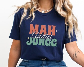 May include: A navy blue t-shirt with the text "MAH Addict JONGG" in a retro font with orange, red, and green colors.