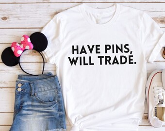 May include: White t-shirt with black text that reads "HAVE PINS, WILL TRADE."