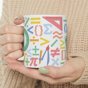 May include: White ceramic mug with a colorful pattern of math symbols, including numbers, equations, and geometric shapes.
