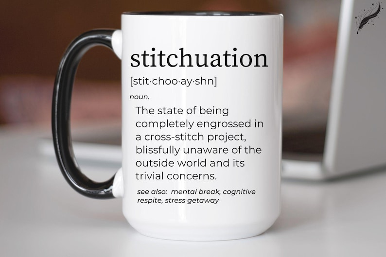 May include: White ceramic mug with a black handle and rim. The mug features the word "stitchuation" in black text, along with a definition. The definition describes being engrossed in a cross-stitch project. The mug is a perfect gift for crafters.